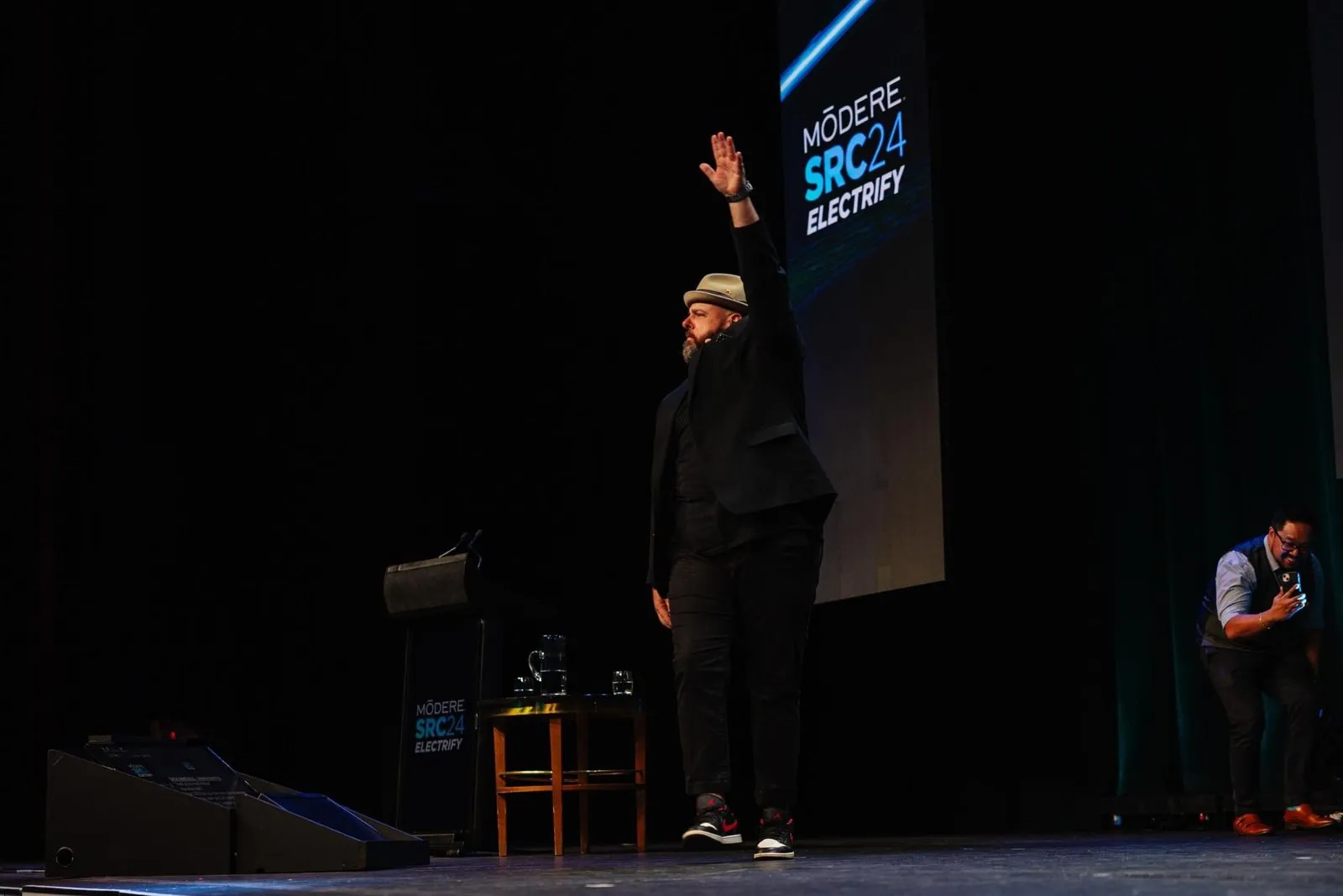 Brett walking on stage with one arm raised high