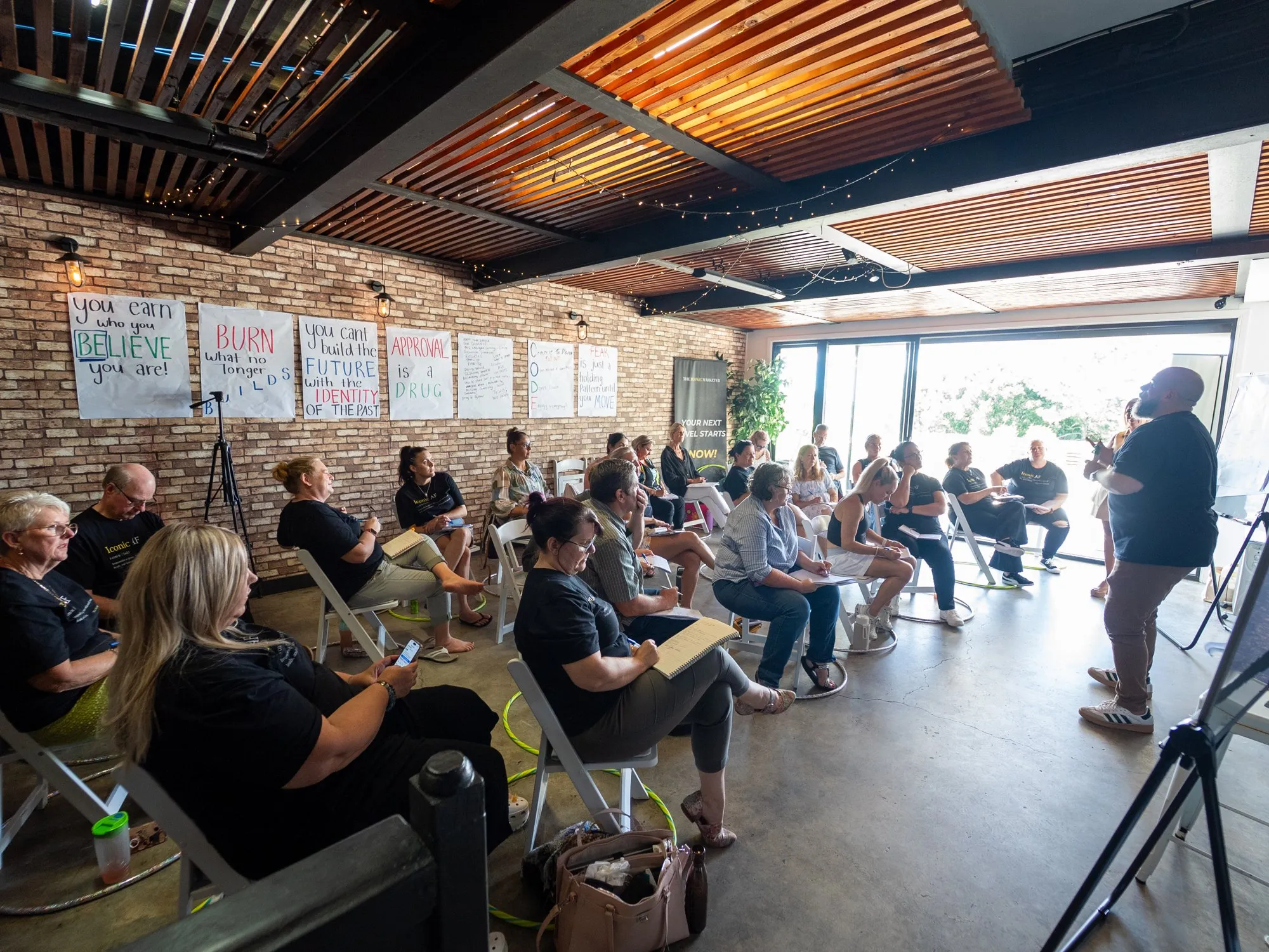 Brett facilitating a session in a full training room, participants seated around tables